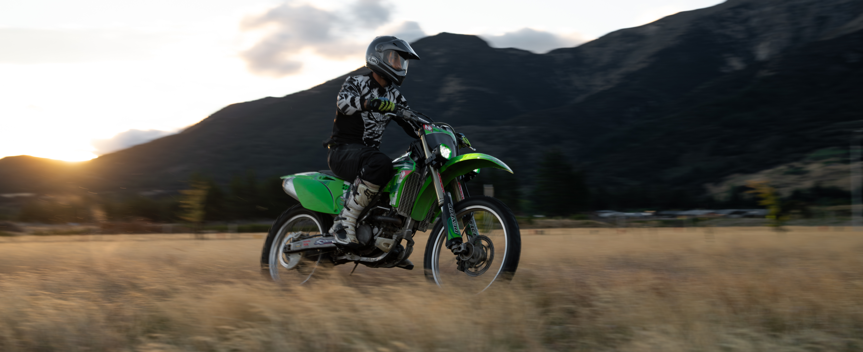 A dirtbike, driving in a field with two EVO Mini driving lights shining.